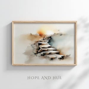 Può includere: Stampa ad acquerello di una scala in pietra che conduce verso un luminoso tramonto dorato. L'opera è incorniciata in una cornice di legno chiaro. Le parole "HOPE AND HUE" sono stampate in basso nell'immagine.