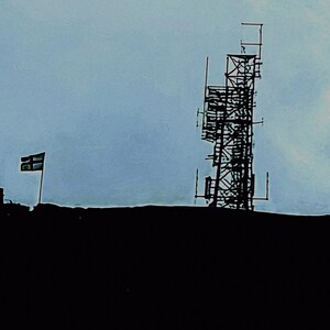 May include: Silhouette of a tall communication tower against a cloudy sky. A flag is visible to the left. The tower has a complex, geometric structure, and the scene is in shades of gray and black.