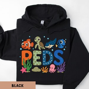 A black hoodie with a colorful graphic design featuring cartoon fish and marine life, along with the letters 'PEDS' arranged in a playful manner.