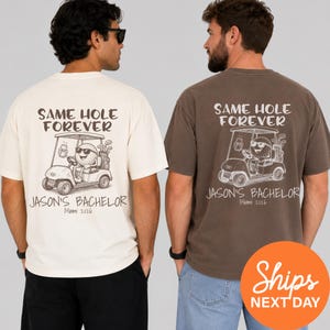 May include: Two t-shirts, one cream and one brown, feature a golf-themed design. The graphic includes a golf ball driving a golf cart with the text "SAME HOLE FOREVER" and "JASON'S BACHELOR Miami 2026".