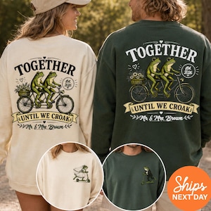 May include: A cream sweatshirt and a dark green sweatshirt, each featuring a graphic of two frogs on a tandem bicycle with the text TOGETHER UNTIL WE CROAK Mr. & Mrs. Brown. Smaller circular insets show a frog in a veil and a frog in a tuxedo.