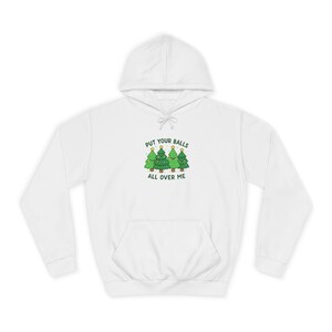 May include: White hoodie with a front pocket and a drawstring. The front graphic shows three green Christmas trees with gold star decorations and the text "PUT YOUR BALLS ALL OVER ME" in green and black.