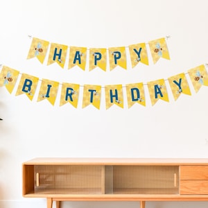 Op de afbeelding: Een geel en blauw "Happy Birthday" spandoek met bijenillustraties. De vlaggen in wimpelvorm spellen "HAPPY BIRTHDAY" in blauwe letters. Elke vlag heeft een honingraatpatroon en een bijenillustratie, perfect voor een verjaardag.
