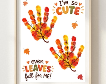 May include: A framed print featuring two handprint-shaped trees with autumn-colored leaves in red, orange, and yellow. The text reads I'm so CUTE and even LEAVES fall for ME! surrounded by small orange and red leaf illustrations on a white background.
