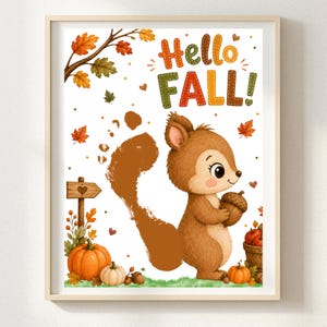 Puede incluir: Una lámina de arte enmarcada que muestra una ardilla marrón sosteniendo una bellota, con el texto Hello FALL! en letras coloridas. La escena incluye calabazas naranjas, hojas de otoño, un letrero de madera con un corazón y una cesta de manzanas rojas.
