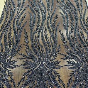 May include: Black beaded fabric with an intricate floral design. The pattern features flowing, stylized plant-like shapes, densely covered in small, dark beads. The fabric has a sheer, light brown background, creating a contrast with the dark beading.