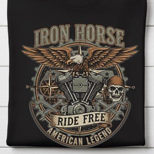 May include: Black t-shirt featuring a motorcycle-themed graphic. The design includes an eagle, engine components, and the text "IRON HORSE", "RIDE FREE", and "AMERICAN LEGEND". The graphic is in shades of brown, tan, and gray.