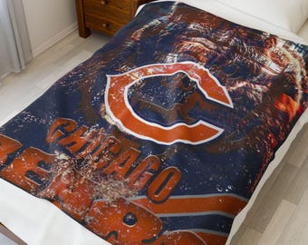 May include: A navy blue and orange Chicago Bears blanket. The blanket displays the team's logo, a large orange "C" with a white outline, and the words "CHICAGO BEARS" in orange. The design has a distressed, vintage appearance.