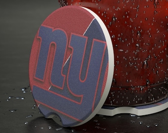 May include: A circular car coaster featuring the letters "NY" in blue, set against a red backdrop with white edging. The coaster is positioned near a glass of red liquid, with condensation.