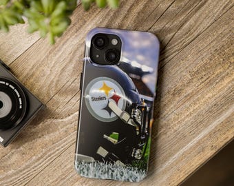 May include: A black phone case with a Pittsburgh Steelers football helmet design. The case features the team's logo with a yellow star and the word "Steelers". The background shows a football field and stadium lights.