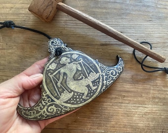 Gongo giratório de bronze: instrumento de percussão manual com baqueta.