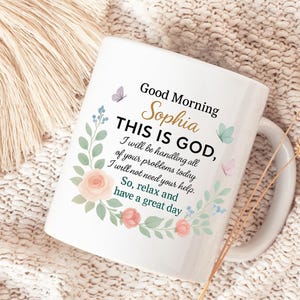 Personalized Christian coffee mug with pastel floral wreath on white ceramic; reads 'Good Morning Sophie' with a gold handle.