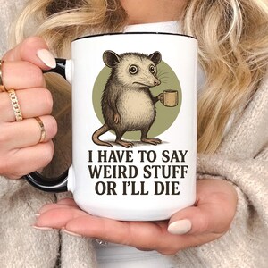 Funny possum mug featuring a cartoon possum holding a cup with a weird stuff quote; quirky office humor mug, coworker gift.