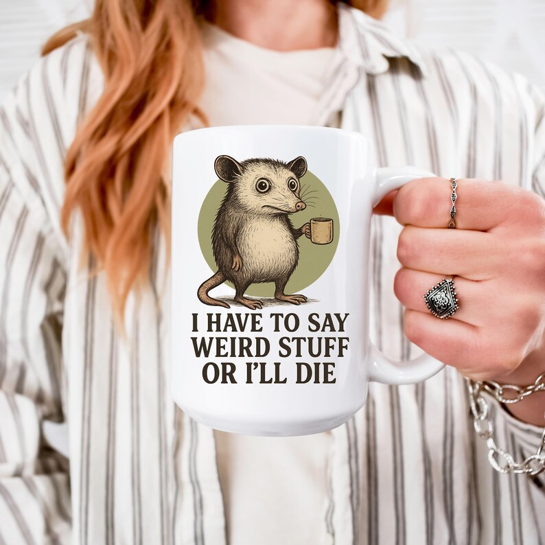 Funny possum mug featuring a cartoon possum holding a cup with a weird stuff quote; quirky office humor mug, coworker gift.