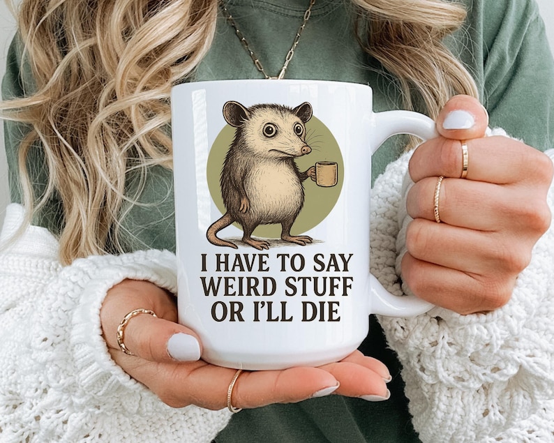 Funny possum mug featuring a cartoon possum holding a cup with a weird stuff quote; quirky office humor mug, coworker gift.