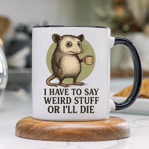 Funny possum mug featuring a cartoon possum holding a cup with a weird stuff quote; quirky office humor mug, coworker gift.