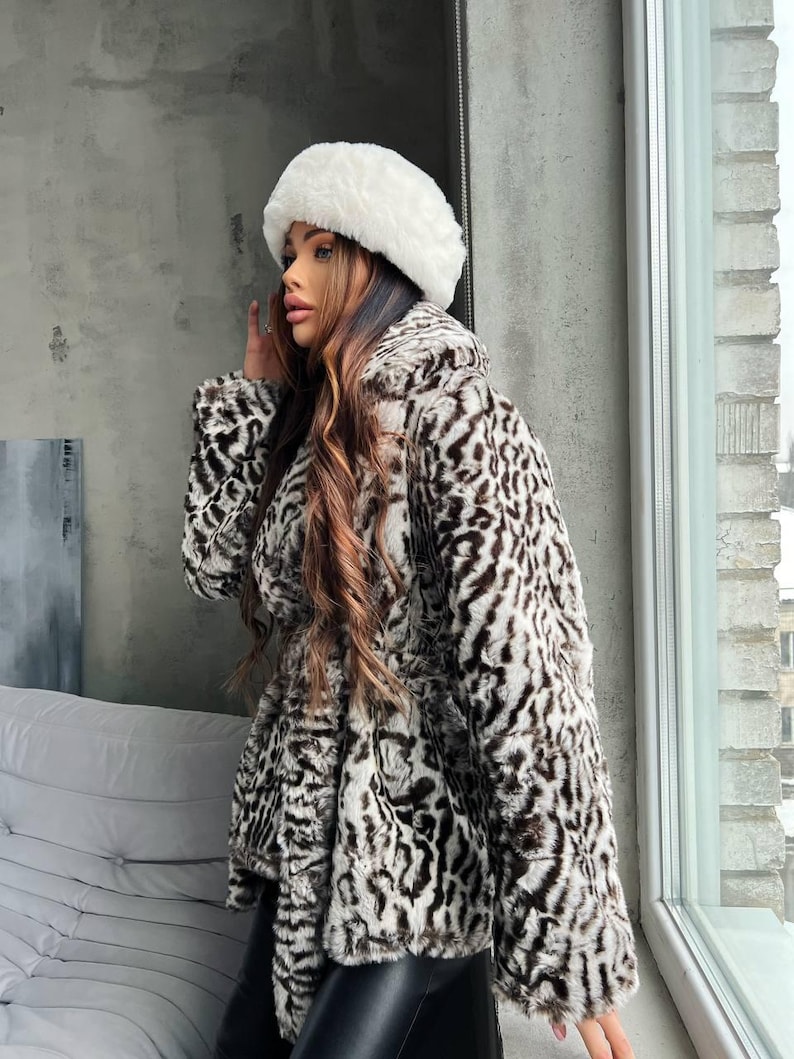 Puede incluir: Un abrigo de piel sint&eacute;tica con estampado de leopardo en tonos marr&oacute;n y blanco. Se combina con pantalones de cuero negro y un gorro de piel blanco. Un conjunto elegante para el invierno.