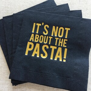 May include: Black paper napkins with gold foil lettering that reads "It's not about the pasta!"