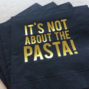 May include: Black napkins with gold foil lettering that reads "It's not about the pasta!"