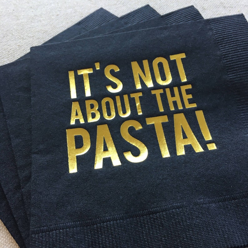 May include: Black napkins with gold foil lettering that reads "It's not about the pasta!"