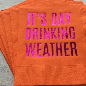 May include: A stack of orange napkins with the text "It's Day Drinking Weather" printed in pink.
