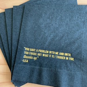 May include: A stack of black napkins with gold lettering that reads "YOU HAVE A PROBLEM WITH ME AND UNTIL YOU FIGURE OUT WHAT IT IS I TRIGGER IN YOU, thumbs up." -LISA
