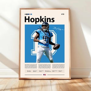 May include: Framed poster featuring a football player in a blue uniform with the number 10. The poster includes the player's name, "Hopkins," and a signature. The background is light blue with white text and a beige border.