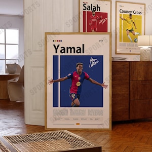 May include: A framed vertical sports poster featuring a photograph of a soccer player in a blue and red jersey with the name Yamal printed in large black letters at the top, accompanied by a white signature and descriptive text blocks below.