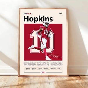 May include: A framed print showcasing a football player in a red uniform with the number 10. The name "Hopkins" is in bold black text above the player. The background is a deep red, and the print is encased in a wooden frame.
