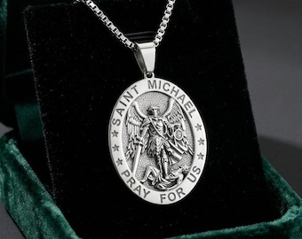 Può includere: Una collana con ciondolo ovale color argento che presenta una raffigurazione in rilievo di San Michele che sconfigge una figura. Il bordo include il testo SAINT MICHAEL PRAY FOR US e quattro stelle. Il ciondolo pende da una catena a scatola.