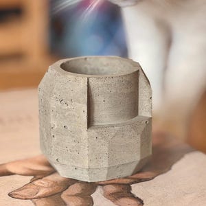 Puede incluir: Una taza de cerámica blanca con un asa negra y el texto "But First, Coffee" en negro, con una fuente de estilo manuscrito. La taza está sobre una superficie blanca.