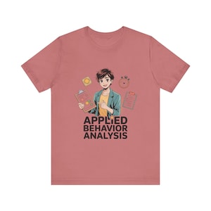 Può includere: T-shirt rosa polveroso con un'illustrazione in stile anime. La grafica include una persona che indica un appunti, con il testo "APPLIED BEHAVIOR ANALYSIS" in nero. Sono presenti anche icone di un timer, una lista di controllo e un pulsante.