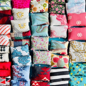 May include: A collection of small, rectangular pillows with various patterns and colors. Designs include floral prints, stripes, and geometric shapes. The pillows are arranged closely together, creating a visually rich and textured display.