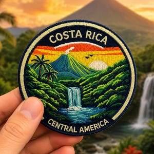 May include: A circular embroidered patch featuring a landscape of Costa Rica. The design includes a volcano, a waterfall, lush green foliage, palm trees, and a sunset sky. The text COSTA RICA is at the top and CENTRAL AMERICA is at the bottom.