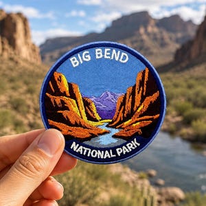 May include: A circular embroidered patch featuring a landscape of Big Bend National Park. The design shows orange and brown canyon walls flanking a blue river, with purple mountains in the distance under a blue sky. The text reads BIG BEND NATIONAL PARK.