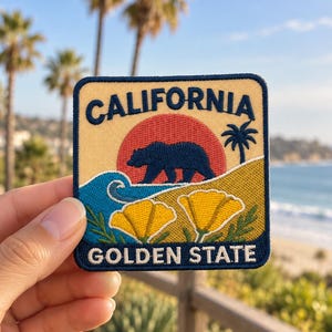 May include: A square embroidered patch featuring the text CALIFORNIA at the top and GOLDEN STATE at the bottom. The design depicts a dark blue bear walking in front of a red sun, a blue ocean wave, a palm tree, and two yellow poppies.
