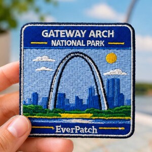 Pode incluir: Um emblema bordado quadrado representando o Parque Nacional Gateway Arch. O design inclui um céu azul, um sol amarelo, nuvens brancas, uma linha de árvores verde e um horizonte urbano azul. O texto diz GATEWAY ARCH NATIONAL PARK e EverPatch.