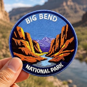 May include: A circular embroidered patch featuring a landscape of Big Bend National Park. The design shows orange canyon walls, a blue river, and purple mountains under a blue sky. The text BIG BEND NATIONAL PARK is stitched in white letters.