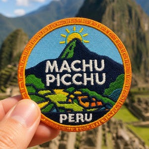 May include: A circular embroidered patch featuring a dark blue mountain silhouette against a light blue sky with a yellow sun. The text MACHU PICCHU is in white, with PERU below. The patch has a bright orange border with a geometric pattern.