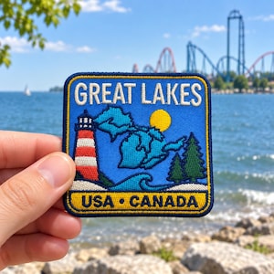 Puede incluir: Un parche bordado cuadrado con fondo azul y el texto GREAT LAKES en blanco. Representa un faro rojo y blanco, un sol amarillo, un mapa de los Grandes Lagos en azul, pinos verdes y la inscripción USA CANADA en color amarillo.