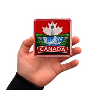 Könnte beinhalten: Quadratischer, gestickter Aufnäher mit rotem Hintergrund, weißem Ahornblatt und einer Darstellung der Niagarafälle. Der Aufnäher enthält das Wort "CANADA" in Weiß auf einem roten Banner. Der Aufnäher hat einen roten Rand.