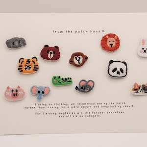 May include: A collection of embroidered animal patches, including a koala, bear, tiger, monkey, lion, panda, rabbit, pig, elephant, mouse, and cat. The patches are colorful and detailed, with a variety of textures. Text on the card reads "from the patch haus".