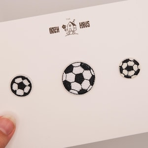 Könnte beinhalten: Drei Fußball-Patches in verschiedenen Größen werden auf einer weißen Karte gezeigt. Die Patches haben ein klassisches Schwarz-Weiß-Design. Die Karte trägt auch den Text "The Patch Haus" und eine kleine Grafik.