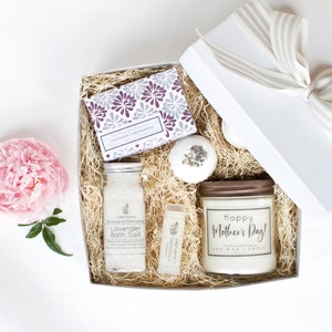 Op de afbeelding: Een witte cadeaudoos gevuld met lavendelbadzout, een lavendelzeep, een badbom en een sojawas-kaars met de tekst "Happy Mother's Day!" op het etiket.