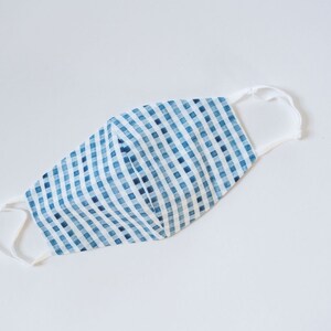 May include: A blue and white gingham face mask with white elastic straps.