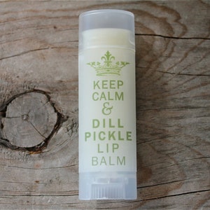 May include: A white tube of lip balm with a green and white label that says "Keep Calm & Dill Pickle Lip Balm".