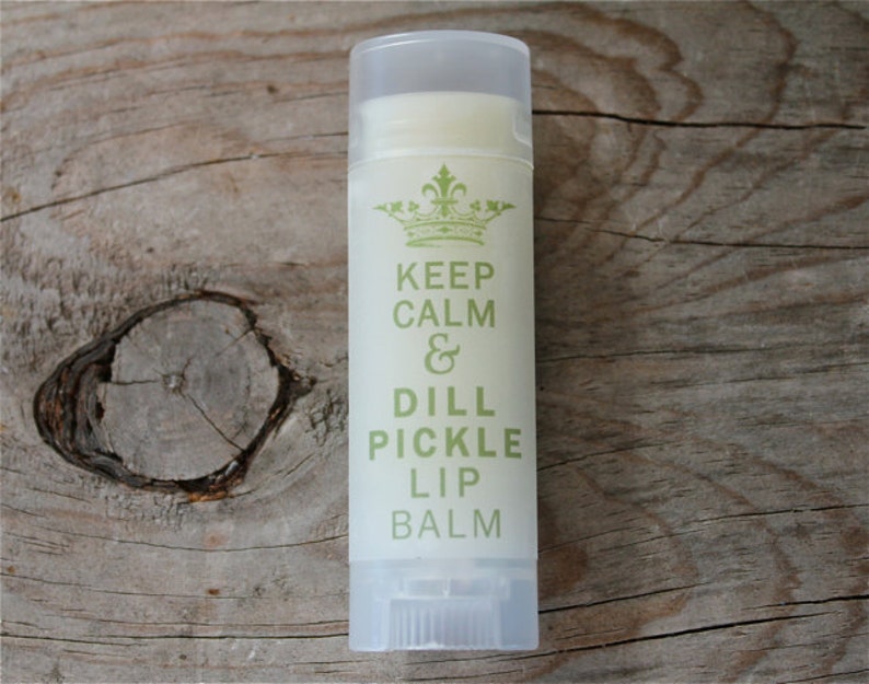 May include: A white tube of lip balm with a green and white label that says "Keep Calm & Dill Pickle Lip Balm".