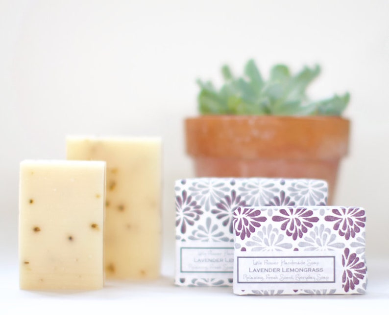 May include: Two bars of white soap with a light green fleck, packaged in a white box with a purple and gray floral design. The box has the text "Lavender Lemongrass" printed on it.