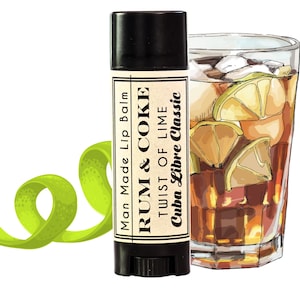 May include: A black lip balm tube with the text "Man Made Lip Balm RUM & COKE TWIST OF LIME Cuba Libre Classic" on the label. A glass of brown liquid with lime wedges and ice is in the background.