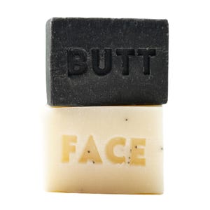 May include: Two bars of soap, one black with the word "BUTT" and one white with the word "FACE" on them.